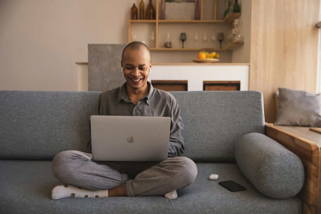 Mann mit Macbook auf Sofa